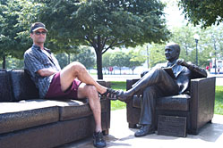 Parry seated upon a hot bronze sofa with a statue of Bob Newhart